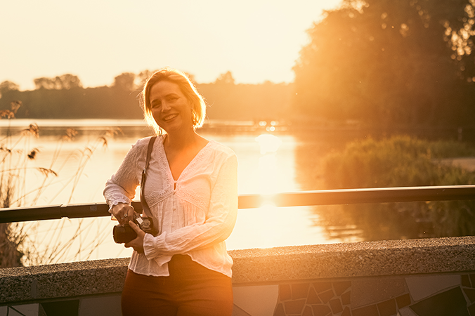 Birth photographer with camera smiling for a photo during golden hour