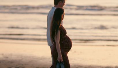 Pregnant woman and partner walking on the beach at sunset. Taken by The Hague birth photographer
