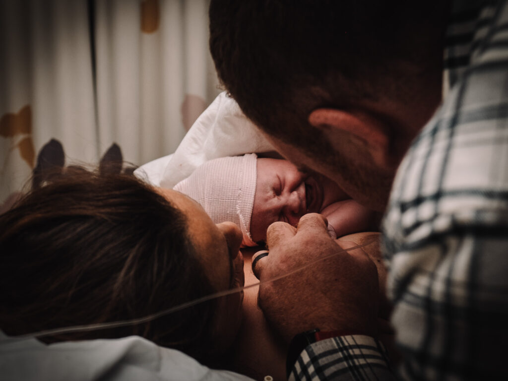 Baby just born on mother's chest with dad