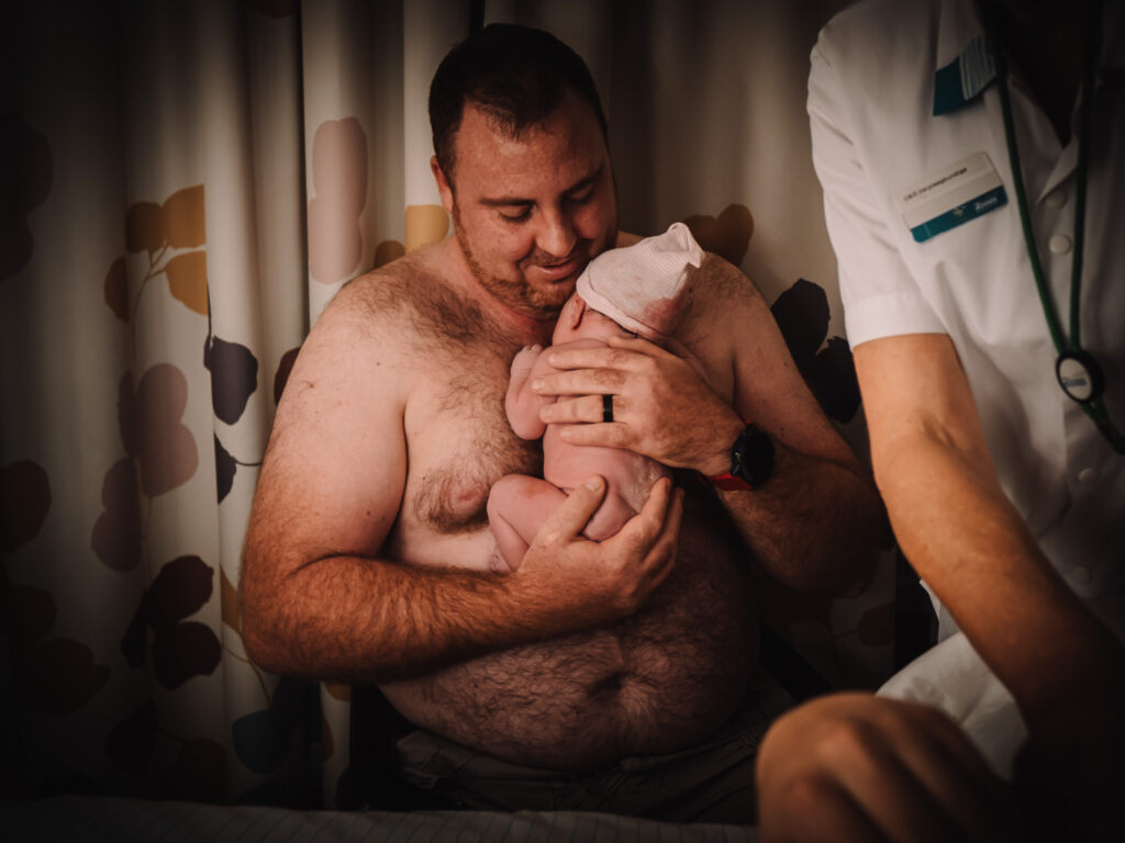 Photograph of dad with newborn baby in hospital