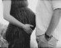 Black and white close up photo of pregnant wife and husband with bellies facing each other.